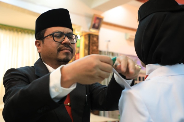 Pj Bupati Aceh Utara Azwardi Abdullah, saat memasang tanda pangkat pada salah seorang Paskibra. Foto: Prokopim/Riki. 