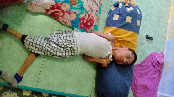 Raja Najwanur (11) putera Erna Dewi, sehari-hari hanya bisa berbaring di atas lantai karena menderita celebral palsy. Foto: Dok. Welita. 