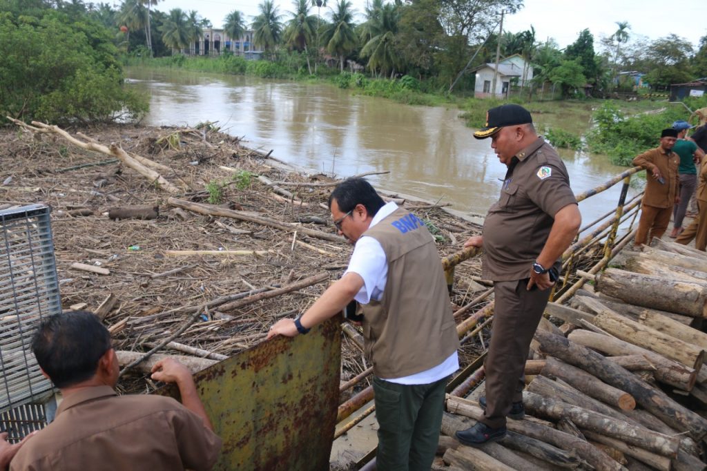 Azwardi memantau sampah yang menyumbat aliran air di jembatan Parang Siukuereung, Matang Kuli. Foto: Komparatif.ID.