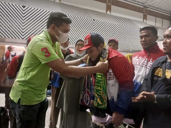 bonek Heru Setiawan dari PB Porwanas, Senin (21/11/2022) mengalungkan selempang persahabatan Aremania dan Bonek ke leher Sekretaris Kontingen PWI Aceh Popon Azwani, setibanya di Bandara Juanda, Surabaya. Foto: Komparatif.id.