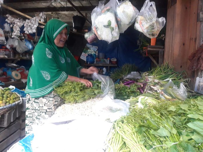 WhatsApp Image 2022-12-27 at 14.28.11 Salah seorang penjual di pasar Pondok Baru, Gayo Bener Meriah sedang mengemas sayuran kepada pelanggan. Foto: Komparatif.ID/Muhajir