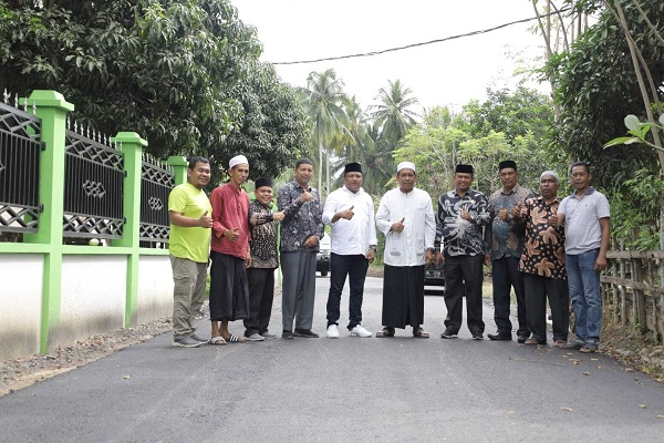jalan-aspal H. Mukhlis (lima dari kiri) dan Teungku Jamaluddin (enam) bersama sejumlah orang berfoto setelah selesainya pengaspalan jalan menuju dayah. Foto: Humas Takabeya.