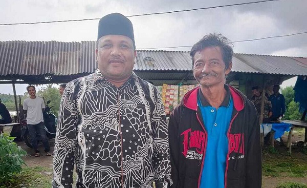 Tersenyum: Amir (48) warga Alue Mangki, gandapura (kanan) tersenyum setelah menerima boat bantuan dari H. Mukhlis (kiri) Direktur PT Takabeya Perkasa Group, Sabtu (21/1/2023).Foto: HO for Komparatif.id