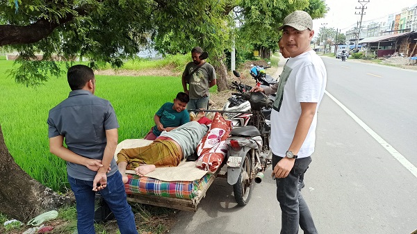 Menghibur sang ayah: Sembari beristirahat, Kamis (26/1/2023) Rahmad bercanda dengan ayanya yang terbaring tak berdaya di atas dipan becak ringkih. Foto: HO for Komparatif.id.