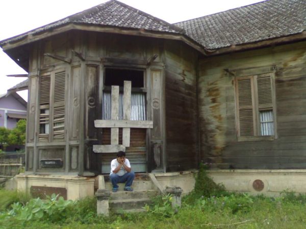 Zulfadli Kawom di teras rumah Ule Balang Krueng Mane Teuku Loethan. Rumah tersebut menjadi saksi sejarah masa lampau. Foto: Koleksi ZK.