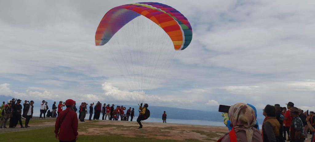 Berlas (27) joki paralayang menunjukan kemampuan terbangnya di Puncak Huta Ginjang, Sabtu (04/02/2023). Foto: Komparatif.ID/Muhajir Juli.