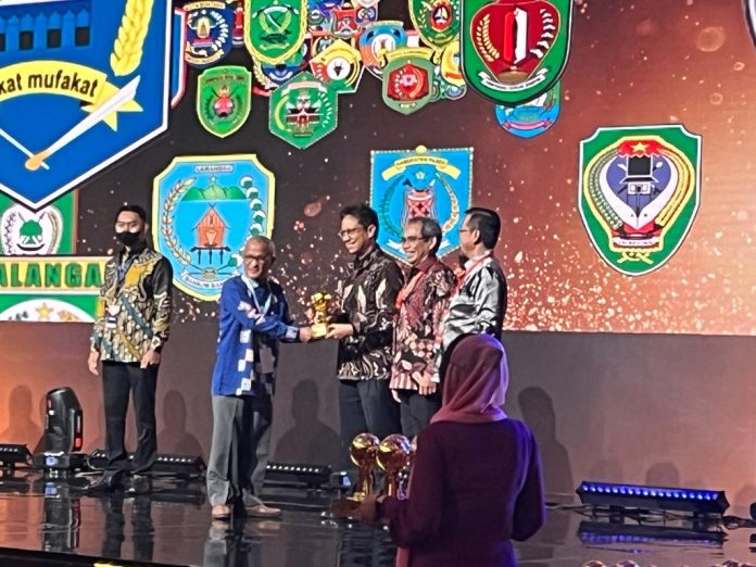 UHC Asisten II Setdakab Aceh Utara Ir Risawan Bentara menerima piagam penghargaan Pemda Berstatus Universal Health Coverage (UHC) di Wapres KH Ma’ruf Amin. Foto: Humas.