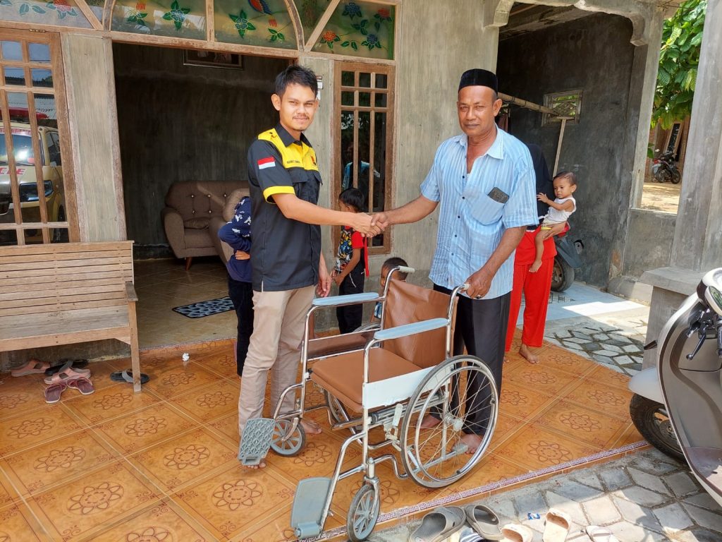 Rahmat T Geurugok, Humas PT Takabeya Perkasa Group saat menyerahkan bantuan kursi roda untuk Rina (26) dari H. Mukhlis A.Md SH, Rabu (19/4/2023). Foto: HO for Komparatif.ID