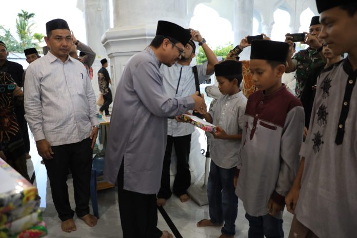 Pj Bupati Aceh Utara Azwardi Abdullah menyerahkan santunan untuk yatim di Gampong Paloh, Kecamatan Tanah Pasir, Selasa (4/4/2023). Foto: HO for Komparatif.ID.