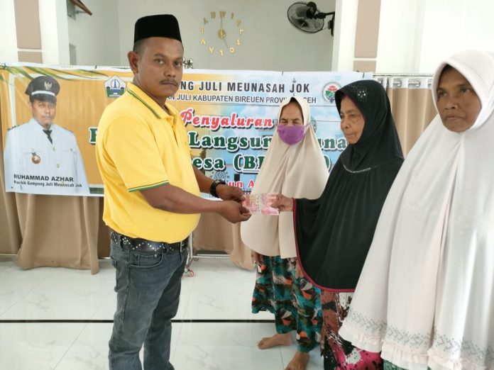 fbf90d1e-7b47-41b3-9f21-e9b98aec82b6 Keuchik Gampong Meunasah Jok, Kecamatan Juli, Muhammad Azhar, Kamis sore (6/4/2023) saat menyerahkan BLT-DD triwulan I 2023 di Meunasah Wakaf Al-Ikhlas. Foto: HO for Komparatif.ID.
