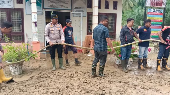 Kapolsek Peudada Aparat polisi Polsek Peudada bersama warga saat membersihkan area Sekolah SDN 17 Peudada pada Jumat (22/9/2023) yang berlumpur usai banjir yang melanda kawasan tersebut. Foto: Ho for Komparatif.ID.