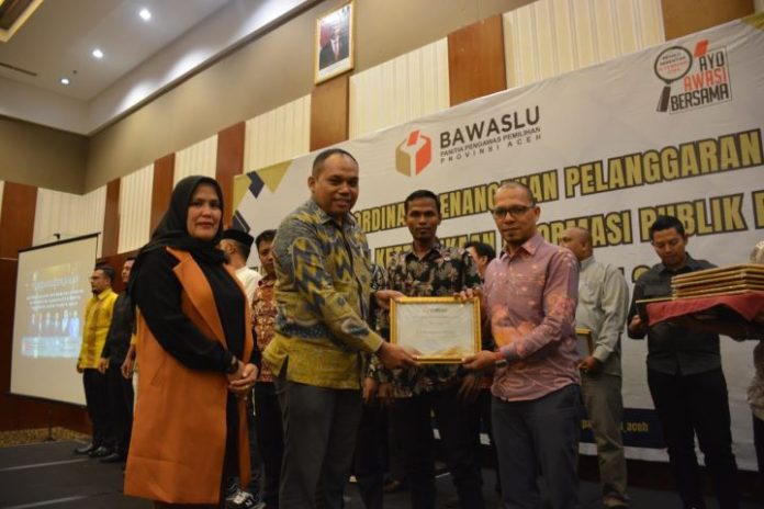Komisioner KIA Arman Fauzi (kiri) saat menyerahkan penghargaan kategori lembaga "informatif" kepada Ketua Panwaslih Bireuen Rahmad, S. Sos., M.A.P (kanan) di Hermes Palace Hotel Banda Aceh, Jumat (29/09/2023). Foto: Ho for Komparatif.ID.