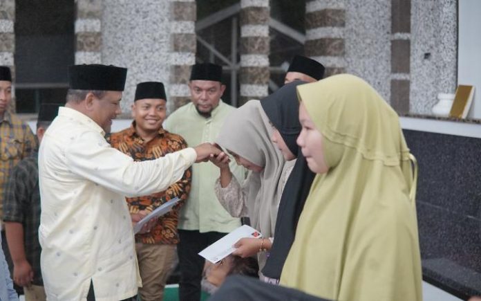 H. Mukhlis Takabeya menyerahkan santunan untuk 100 anak yatim di Masjid Syuhada Lapan di gampong Keude Tambue, Kecamatan Simpang Mamplam, Sabtu (30/3/2024).