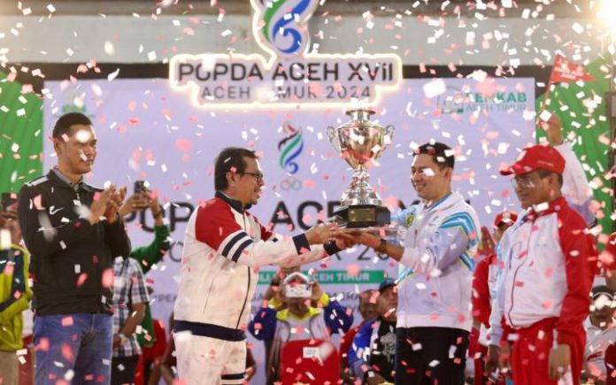 Popda Aceh TImur Banda Aceh Juara Umum Popda, Bireuen Peringkat 9 Pj Sekda Aceh Azwardi Abdullah menyerahkan piala bergilir Gubernur kepada Pj Sekda Banda Aceh pada penutupan Popda XVII Aceh Timur, Jumat (12/7/2024) malam. Foto: Humas Aceh.