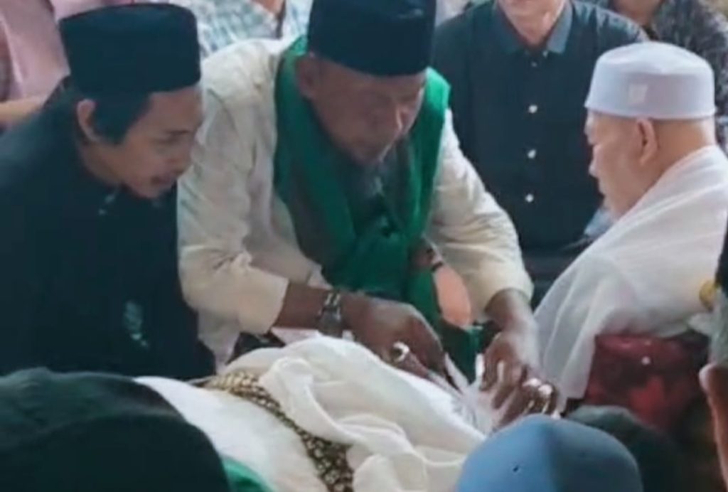 Putra Sulung Tu Sop Tiba, Lihat Wajah sang Ayah Terakhir Kali Teungku Muzammil (kiri) menunggu Abi Nas membuka kain kafan sang ayahanda Teungku H. Muhammad Yusuf A. Wahab. Muzammil merupakan putra sulung Tu Sop yang saat ini sedang studi di Turki. Foto: Komparatif.ID.