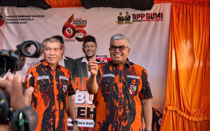 Bustami Pemuda Pancasila Kader Pemuda Pancasila: Bustami Gubernur Aceh! Calon Gubernur Aceh nomor urut 1 Bustami Hamzah (Om Bus) memperlihatkan KTA Pemuda Pancasila sebelum pengukuhan RPP BUMI se-Aceh di RKB Pusat, Banda Aceh, Selasa (29/10/2024). Foto: Komparatif.ID/Fuad Saputra.