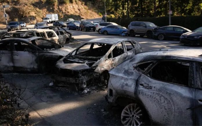 Kebakaran Los Angeles: Korban Bertambah, Api Masih Sulit Dipadamkan Mobil-mobil terbengkalai, beberapa terbakar akibat kebakaran Palisades, tergeletak di pinggir jalan di Pacific Palisades. Foto: John Locher/AP.